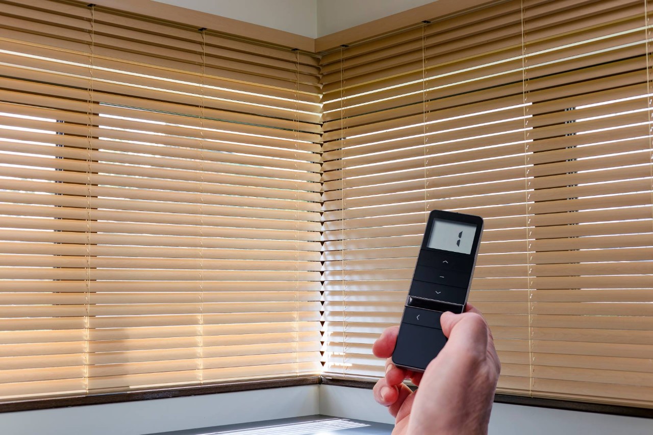 A woman's hand holding a remote to adjust motorized blinds at Little’s Custom Blinds & Shutters near Brunswick, GA